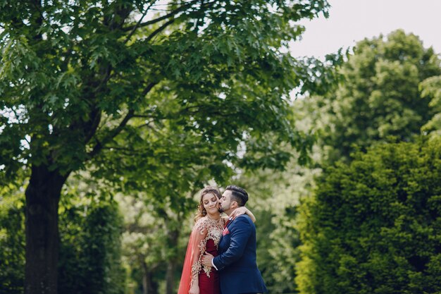 Beautiful woman in a long red dress walks around the city with her husband