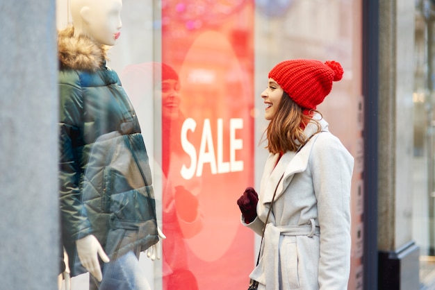 Бесплатное фото Красивая женщина смотрит в окно магазина во время покупок