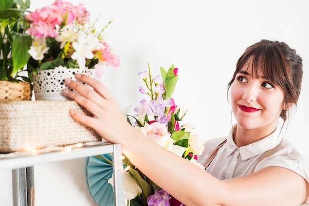 Beautiful woman looking at fresh flowers on shelf