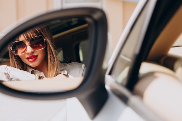 Beautiful woman looking into car mirror