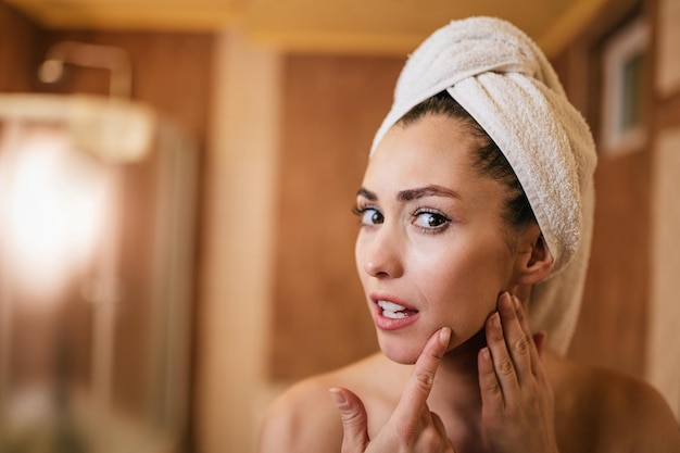 Beautiful woman looking for wrinkles on her face skin in the bathroom