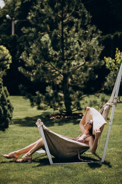 Beautiful woman lying in hammock wearing big sunhat