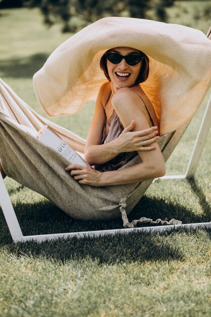 Beautiful woman lying in hammock wearing big sunhat