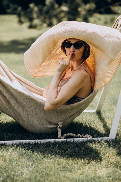 Beautiful woman lying in hammock wearing big sunhat