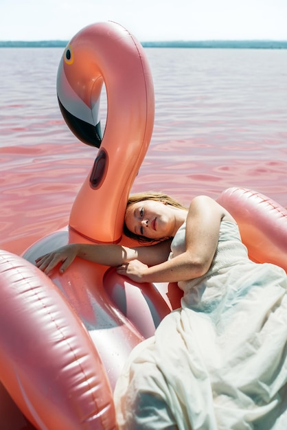 Красивая женщина, лежа на надувной матрас поплавок на розовом море