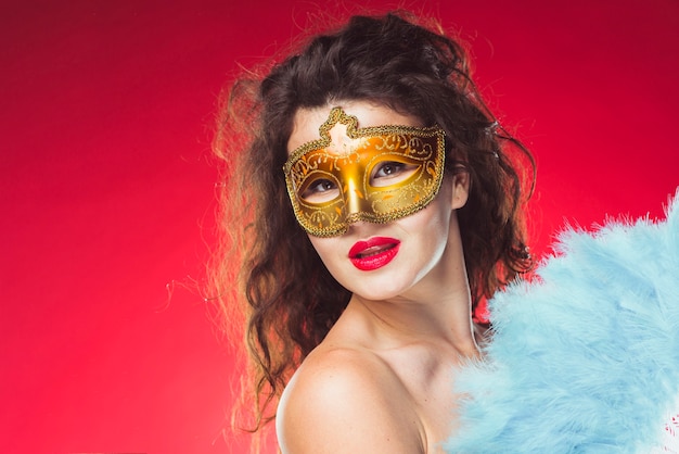 Free photo beautiful woman in mask with feather fan