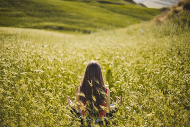 Free photo beautiful woman meditating in green field
