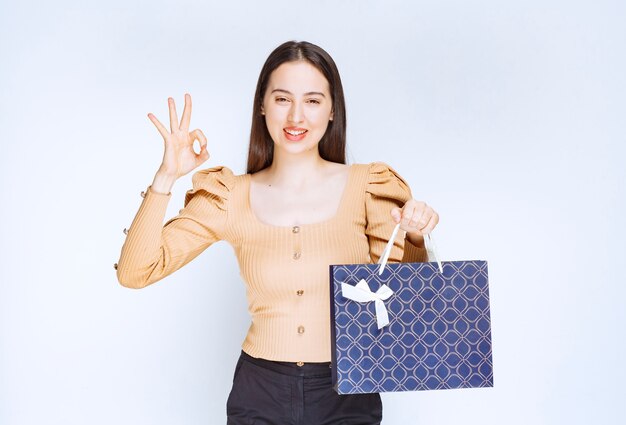 A beautiful woman model with a shopping bag showing ok gesture .