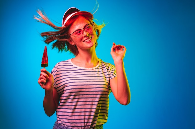 Beautiful woman in neon light isolated on blue studio