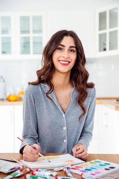 Beautiful woman painting in kitchen