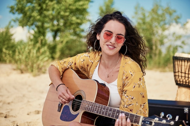 Красивая женщина играет на гитаре на пляже