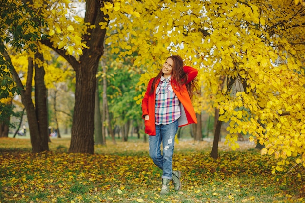 秋の公園を歩きながら髪と遊ぶ美しい女性