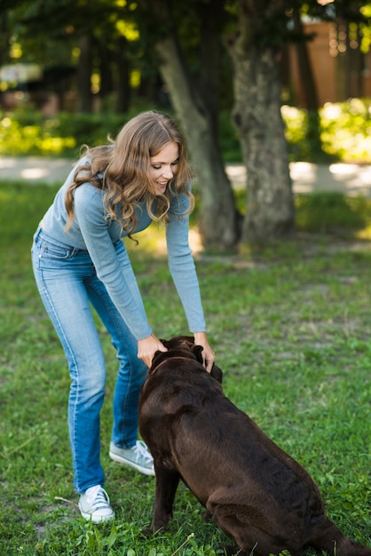 Foto gratuita bella donna che gioca con il suo cane nel parco