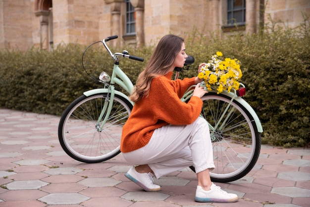 屋外の花と自転車の横にポーズをとって美しい女性