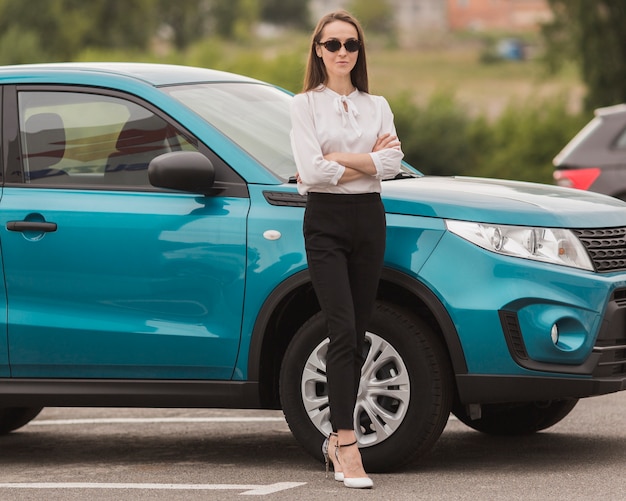 Foto gratuita bella donna che posa davanti all'automobile moderna