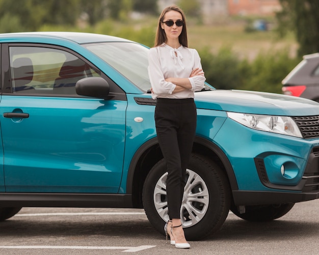 Beautiful woman posing in front of modern car
