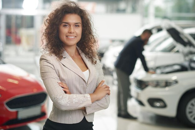 Beautiful woman posing smiling in car showroom