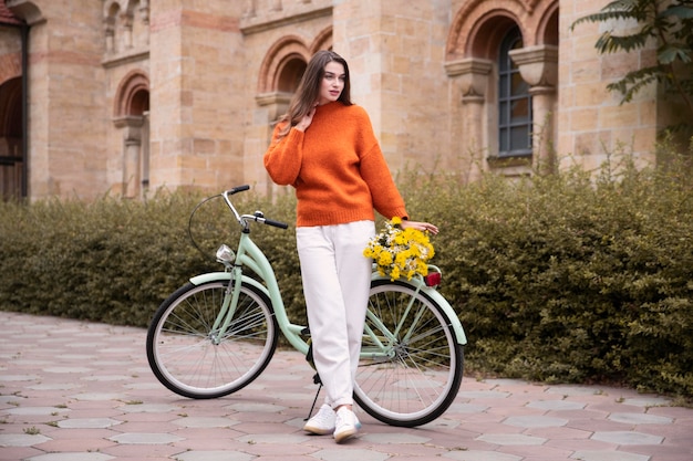 Bella donna in posa con la bicicletta e fiori all'esterno