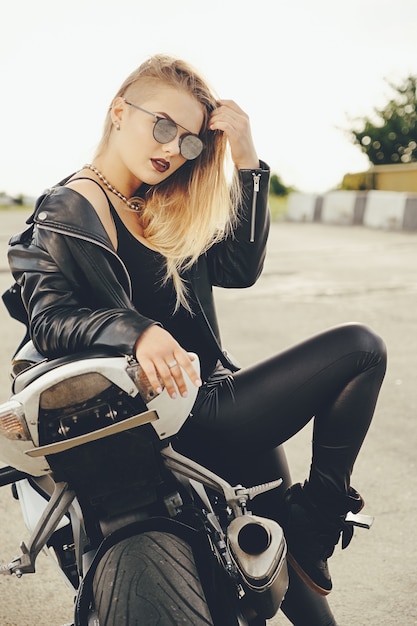 Beautiful woman posing with sunglasses on a motorbike