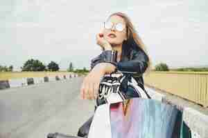 Free photo beautiful woman posing with sunglasses on a motorbike