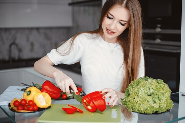 美しい女性は台所で食べ物を準備します。