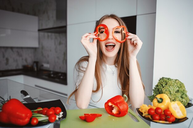 美しい女性は台所で食べ物を準備します。