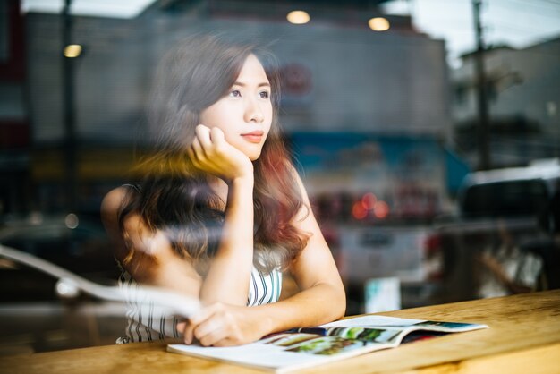 Beautiful woman reading magazine in cafe