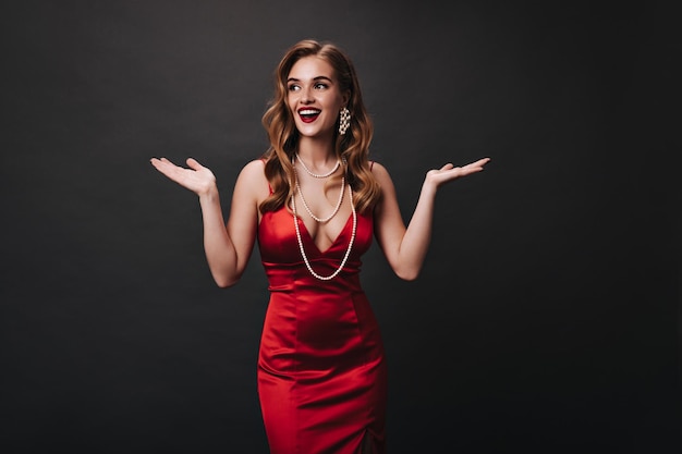 Free photo beautiful woman in red outfit smiling on black background