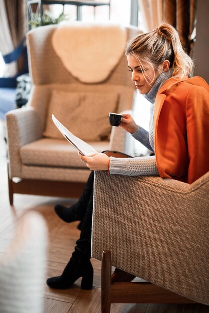 카페테리아에서 일간 신문을 읽으면서 커피 시간 동안 휴식을 취하는 아름다운 여성