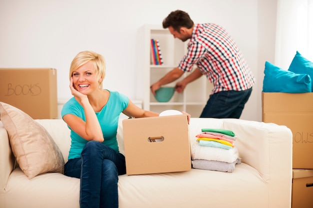 Beautiful woman resting on couch while her husband decorating their new living room