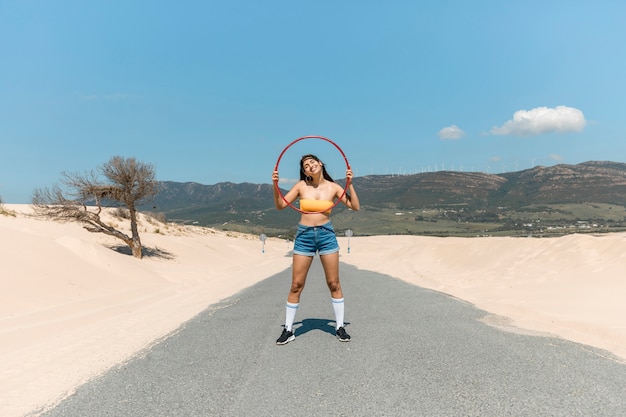 Bella donna sulla strada in posa con hula hoop