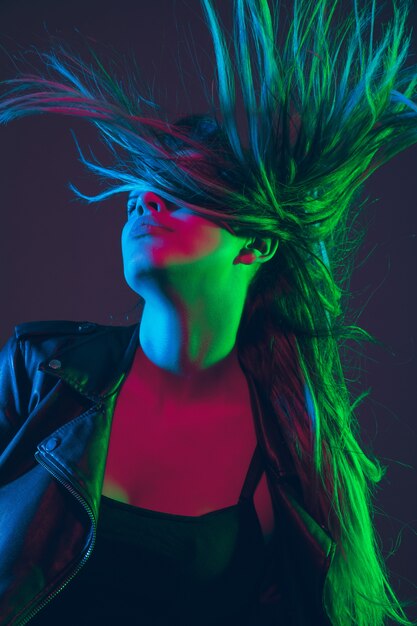 Beautiful woman's portrait with blowing hair in colorful neon light