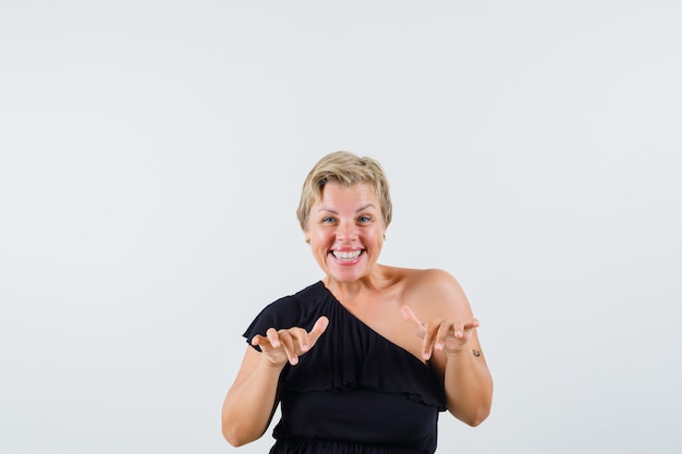 Beautiful woman showing bunny gesture in black blouse and looking amused