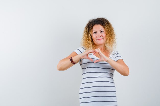 Beautiful woman showing love gesture in t-shirt and looking frank , front view.