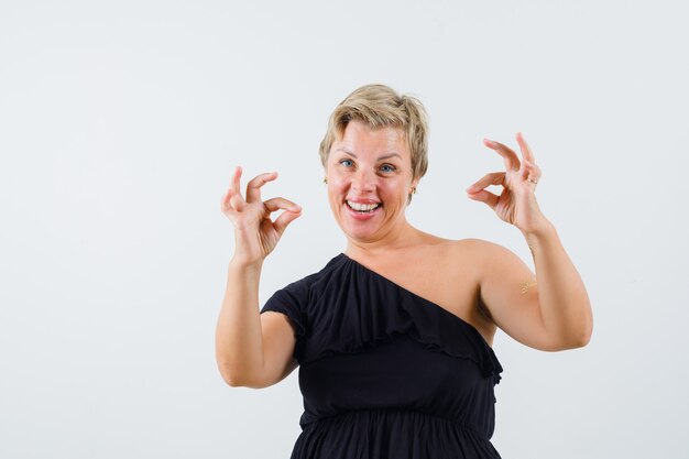 Beautiful woman showing ok gesture in black blouse and looking merry