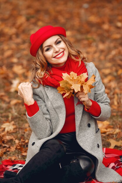 秋の公園に座っている美しい女性