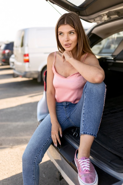 Beautiful woman sitting on a car trunk