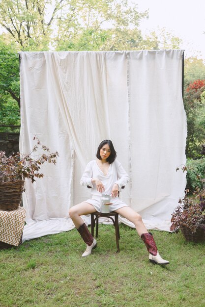 Beautiful woman sitting on a chair in garden .