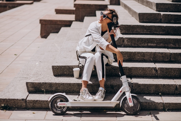 Free Photo beautiful woman sitting on stairs with her scooter