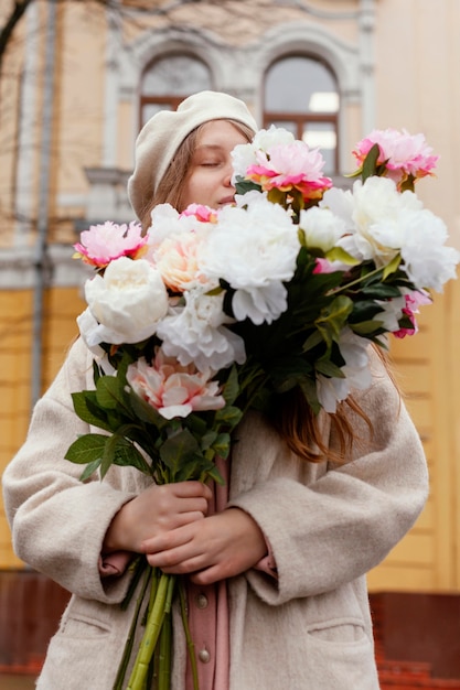 Foto gratuita bella donna che sente l'odore di un mazzo di fiori all'aperto