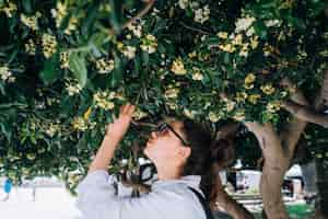 Free photo beautiful woman smelling trees' flowers. spring time