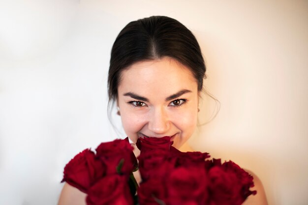 赤いバラのバレンタインデーの花束を笑顔で保持している美しい女性
