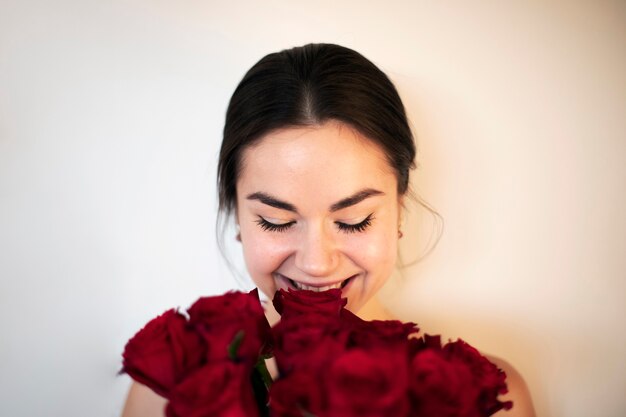 Bella donna che sorride e tiene in mano un mazzo di rose rosse per san valentino