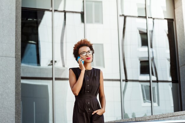 Beautiful woman smiling speaking on phone walking down city