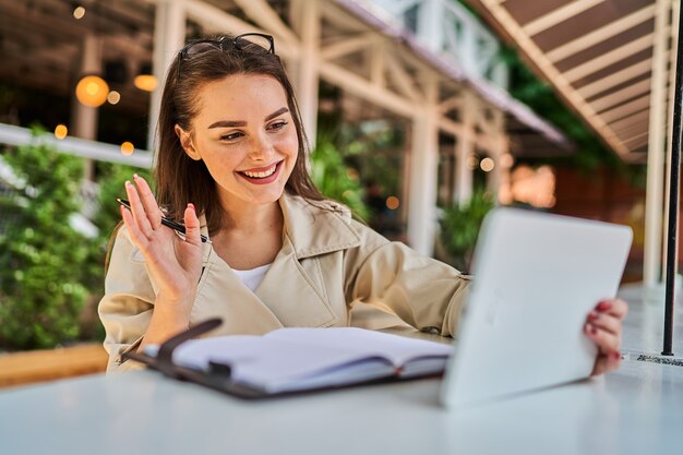 Beautiful woman speaking by video call with tablet outdoors