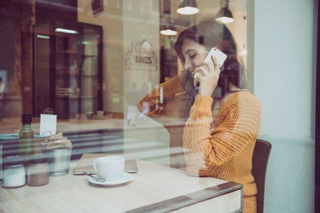 Beautiful woman speaking on phone in cafe