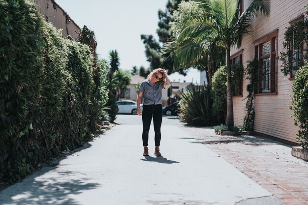 Beautiful woman standing on an empty pathway fixing her hair