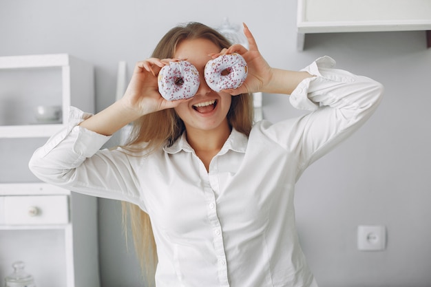 Beautiful woman standing in a kitchen with donut