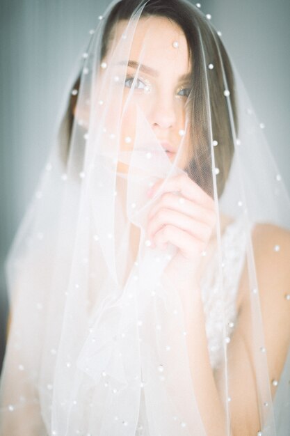 Beautiful woman standing and looking in wedding dress in room