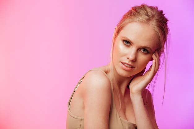 Beautiful woman standing and posing over pink wall